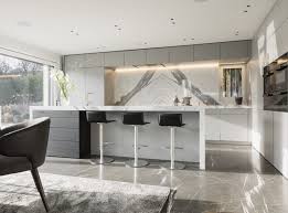 Die Kochinsel Der Luxus Kuche Bildet Den Gewunschten Kontrast Zu Dem Dunkleren Naturstein Boden Schlafzimmer Design Kuche Nach Mass Kuche