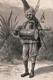 A Hindu ascetic, or holy man: standing, beating a drum with his left hand and plucking a stringed instrument with his right hand. Wood engraving by M. Klinkicht, 1876. | Wellcome Collection
