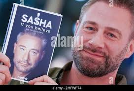 Hamburg, Germany. 17th Jan, 2022. Singer and musician Sasha holds up his  first book "If You Believe