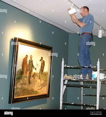 Tom Merrill adjusts the lighting for "The Meeting, 1854" by Gustave Courbet  at the "Bonjour, Monsieur Courbet!" exhibit at the Sterling & Francine  Clark Art Institute in Williamstown, Mass., Wednesday, June 23,