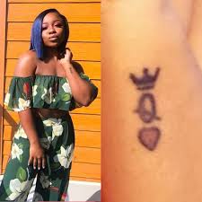 Grey ink queen band tattoo on upper back. Celebrity Queen Tattoos Steal Her Style