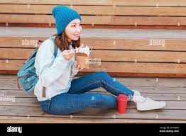 Fashionable asian teen hipster girl eats Oriental wok noodles with  chopsticks. Concept of lunch and natural takeaway containers made of paper  Stock Photo 