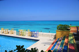 A stylish crowd sips potent cocktails on the pool deck with the deep blue sea as a backdrop. Hells Bells Auf Den Bahamas Compass Point Mk