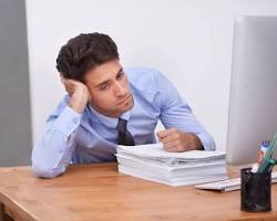 Image of boredlooking person sitting at a desk surrounded by legal documents