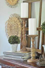 A young woman in a black mantle with a striped scarf around her neck casts a spell from a book and conjures with a wand of magic. How To Decorate Your Farmhouse Style Mantel For Summer Mantel Decor Everyday Candle Stick Decor Summer Mantel