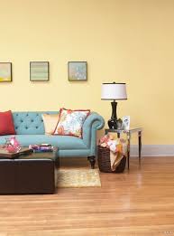 Furnishing in pale neutral tones and dark woods add both contrast and visual interest while enhancing the room's modern vibe. Blue Couch With Warm Yellow Wall And Pops Of Red Yellow Walls Living Room Living Room Colors Blue Living Room