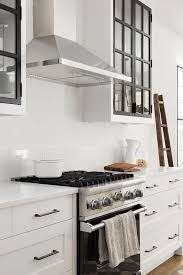 Black And White Glass Front Upper Kitchen Cabinets Flank A Stainless Steel Vent Ho Glass Fronted Kitchen Cabinets Upper Kitchen Cabinets Kitchen Cabinet Design