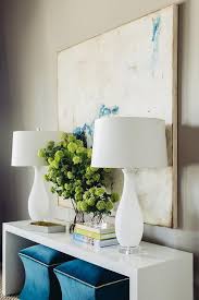 Two Sapphire Blue Ottomans Sit Beneath A White Lacquered Waterfall Console Table Topped With Dining Room Console Table Dining Room Console White Console Table