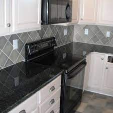 This white kitchen features black and grey accents which give it a stylish almost art deco feel. Stunning Absolute Black Granite Combined With Nice Kitchen Lamp Color Custom Kitchen Area W Backsplash For White Cabinets Grey Backsplash Gray Tile Backsplash