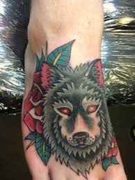 This traditional wolf design on the foot demonstrates a smoky wolf with red eyes and two roses on the edges of the tattoo. 40 Traditional Wolf Tattoo Ideas August 2021