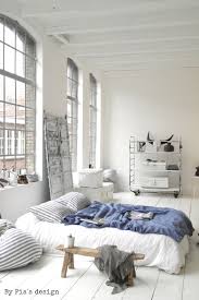 All White Minimalistic Bedroom With Bed On The Floor Natural Light Big Windows Blue Blanket Accent Minimalism Interior Bedroom Design Minimalist Bedroom