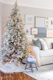 A Snowy Flocked Christmas Tree Decorated In Silver And Rose Gold Adds A Big Dos Frosted Christmas Tree Flocked Christmas Trees Decorated Christmas Living Rooms