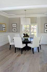 A large solid surface dining table graces the floor along with white leather dining chairs, a stylish hung art piece, and beautiful modern chandeliers. Dining Room Wainscoting French White Oak Floor Ceiling Design House Interior White Oak Floors Home Decor
