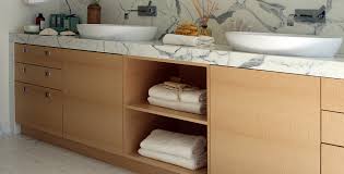 A sleek and stylish cabinet finished in sycamore black with drop handles in antiqued brass. Flawless Movement Custom English Sycamore Veneer Bathroom Cabinetry