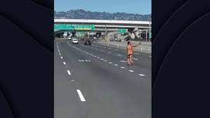 Una mujer camina desnuda por una autopista mientras dispara a los coches  con una pistola