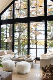 American Lake House Living Room With Floor To Ceiling Framed Windows With Lake View Lake House Interior Lake House Living Room House Design