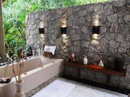 An uplighted river rock bathtub is placed in the back of a reclaimed wooden house, along with the wall mounted the outdoor bathroom ideas should come with suitable privacy. Goodshomedesign