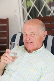 Asian Man Holds a Glass of Water Over the Blue Sky Stock Photo