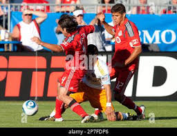 Toronto FC's Nick Garcia, left, and Adrian Cann, right,crowd out Houston  Dynamo's Danny Cruz during first-half MLS soccer game action in Toronto