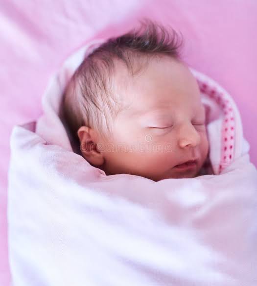A newborn baby girl wrapped in a hospital blanket, representing the miracle birth in Greece.