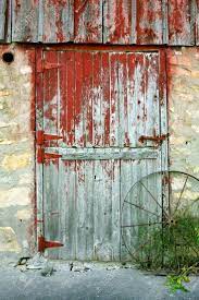 Unique rustic barn door entrance to building with reflection of nature in one side with glass panes all set in brick with red. Peeling Barn Paint Google Search Old Barn Doors Rustic Doors Red Barn Door