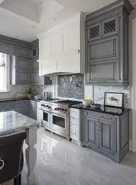 What kind of kitchen cabinets are gray and white? White Kitchen Hood With Dark Gray Mosaic Cooktop Backsplash Tiles Transitional Kitchen Kitchen Cabinet Design Grey Kitchen Kitchen Design