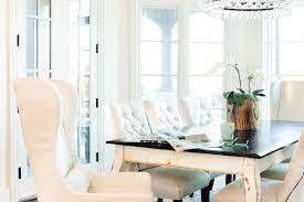 The dining set, which includes a round table. White French Dining Table With Black Top And White Tufted Dining Chairs Transitional Dining Room