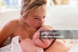 Caucasian Girl Kissing Newborn Baby In Bath High-Res Stock Photo