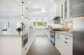 Simple white mission cabinets and a long island with marble counters create a nice contrast with the brown hardwood flooring. Wide Plank Kitchen Floors With White Cabinets Transitional Kitchen