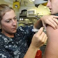 US Navy 111125-N-ZN781-020 Hospital Corpsman 1st Class Samuel Karr  administers a smallpox vaccine to Gunner's Mate Seaman Brandon Tokarski  during a