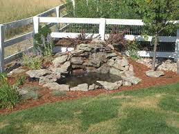 Small Diy Ponds With Waterfall And Stone Border In The Corner Backyard Garden House Design With Wooden Fence And Ra Waterfalls Backyard Ponds Backyard Diy Pond