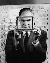 glenn t seaborg in front of a periodic chart of the atoms