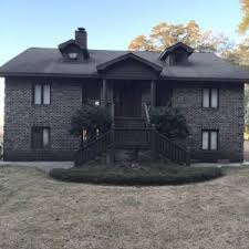 Painted white brick house with board and batten over garage, black trim, black soffit, black fascia, black garage door, black door, black windows, arched entry. Black Brick House Brick Exterior House Black Brick House Dark Brick House Exterior