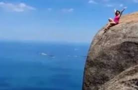 Differential weathering on one side of the rock has created what is described as a stylized human face, and weathered markings on another face of the rock have been described as an inscription. Tourist Posing On 2 800 Foot Mountain Edge Pedra Da Gavea Brazil World News