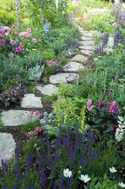 A flagstone pathway leads through a lush garden and along the side of a house. Pin On Garden Pathways