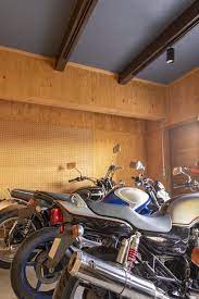 バイクガレージの壁は 釘を打ったり工具をかけたりできるように 合板 有孔ボードで仕上ました バイクを照らすスポットライトや ファクトリーテイストのスイッチにもこだわっています ガレージの壁 ガレージ ガレージハウス