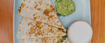 Three tacos in flour tortillas with pico, avocado, mixed cheese, jalapeño aioli, cilantro, queso fresco. Fish Taco