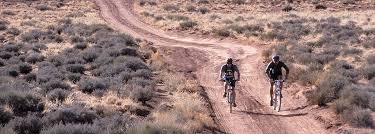 The image shows two people riding bicycles on a trail in Western Colorado.