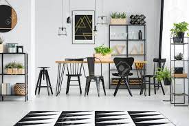 This dining room incorporates furniture from a number. Black Chairs At Table In Scandinavian Style Dining Room With Geometric Carpet And Ferns Stock Photo Picture And Royalty Free Image Image 97990937