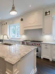 White farmhouse sink with granite countertops and chocolate cabinets. White Kitchen Ideas Super White Granite Cc40 Cabinetry Decorative Hood Wolf Range Prasada Custom H Super White Granite White Kitchen Dark Kitchen Cabinets