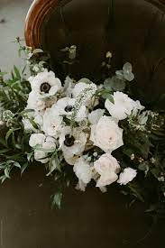 Beautiful fresh soft wedding decorative round shape bouquet of pink rose white peony and green flowers lying on black glossy background outdoor, horizontal picture. Simple White And Green Wedding Bouquet With Vines And White Flowers By Jess Craven