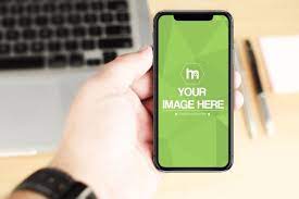 Download A Mockup Featuring A Man Holding An Iphone X On A Blurred Office Desk Background A Great Template For Showcasing Your Ios App Iphone Mockup Laptop Backgrounds