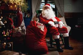 Find the perfect santa sitting stock illustrations from getty images. Portrait Of Santa Claus Sitting In Chair With Sack Full Of Presents Stock Photo Dissolve