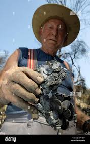 Lew Johnson, 74, holds coins that have melted together, as he returns for  the first time to the ruins of his home