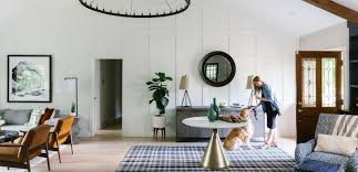 The interior of the living room with a beige armchair and a vase by the window and a palm tree near the door. Online Interior Design And Home Decorating Havenly