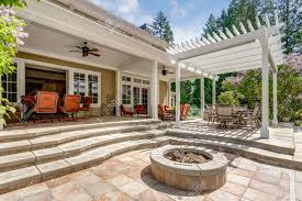 A fire bowl sits under a timber frame pergola for shade over backyard patio with wire metal outdoor furniture. Lovely Outdoor Deck Patio Space With White Pergola Fire Pit In The Backyard Of A Luxury House Stock Photo Picture And Royalty Free Image Image 107897680
