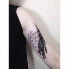 Seigaiha patterned abstract tattoo on the left arm.