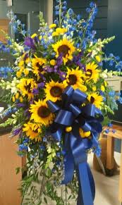 All of our funeral flowers are guaranteed and our customer service cannot be matched. Standing Funeral Spray In Blue And Yellow With Iris Sunflowers Delphinium And Larkspur Funeral Flowers Funeral Sprays Funeral Flower Arrangements