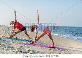 Yoga teen, yoga worrkout, perfect teen yoga yoga for young woman, girls in yoga pants. Young Women Practicing Yoga On The Beach Beautiful Girls Doing Yoga Standing In Warrior Pose At