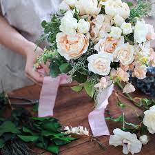 11月の花嫁さまへブラッシュピンクのクラッチブーケ 淡いあわいピーチピンクのお花をたっぷり合わせたクラッチブーケ リボンの色合わせ作業中です シフォンのドレスにあわせてリボンももっとたっぷりになりましたよ 大切な日のお花をおまかせいただきましてありがとう